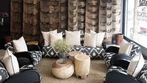 A seating area with patterned sofas, wooden side tables, and a decorative wall with carved figures. - The Bridge An Eclectic Luxotel Chiangmai (Chiang Mai)