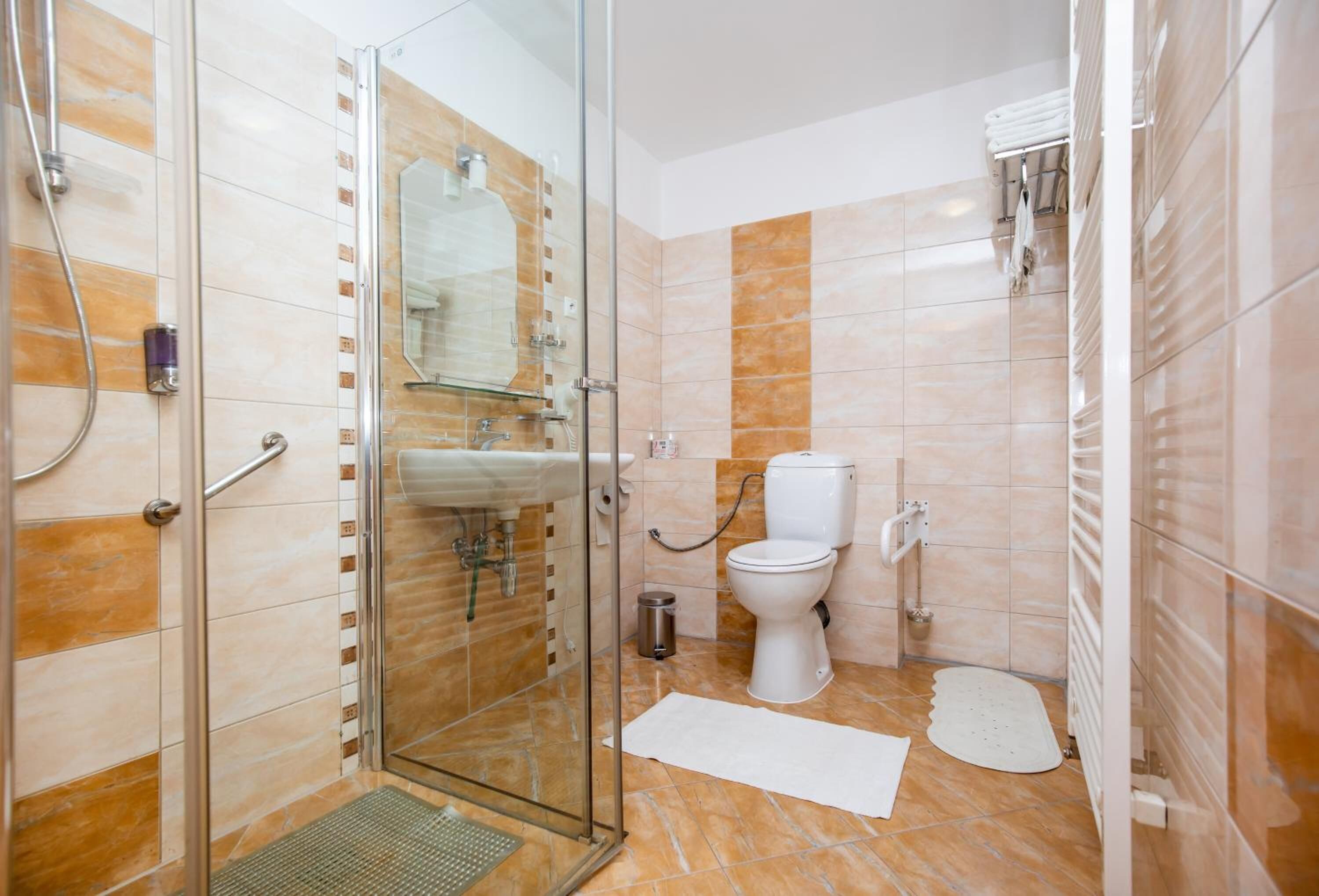 A bathroom with a glass shower enclosure, a toilet, and a sink.