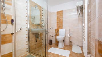 A bathroom with a glass shower enclosure, a toilet, and a sink.