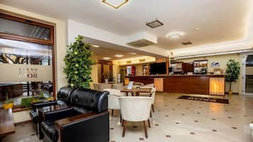 A hotel lobby with leather seating, a reception desk, and a bar area.