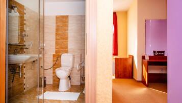 A bathroom with a glass shower enclosure, a toilet, and a sink.