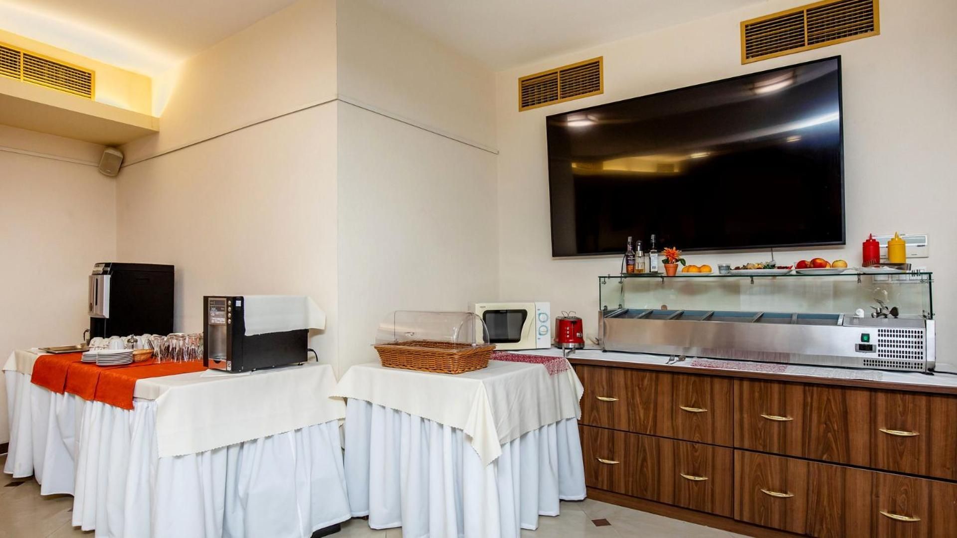 Ein Hotelzimmer mit Küchenzeile, einem Flachbildfernseher, einem Buffet und einem großen Fenster.