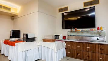 Ein Hotelzimmer mit Küchenzeile, einem Flachbildfernseher, einem Buffet und einem großen Fenster.