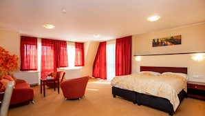 Quarto de hotel com cama, escrivaninha, cadeira e radiador.