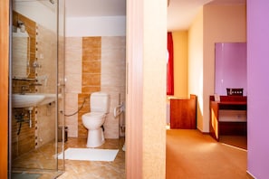 A bathroom with a glass shower enclosure, a toilet, and a sink.