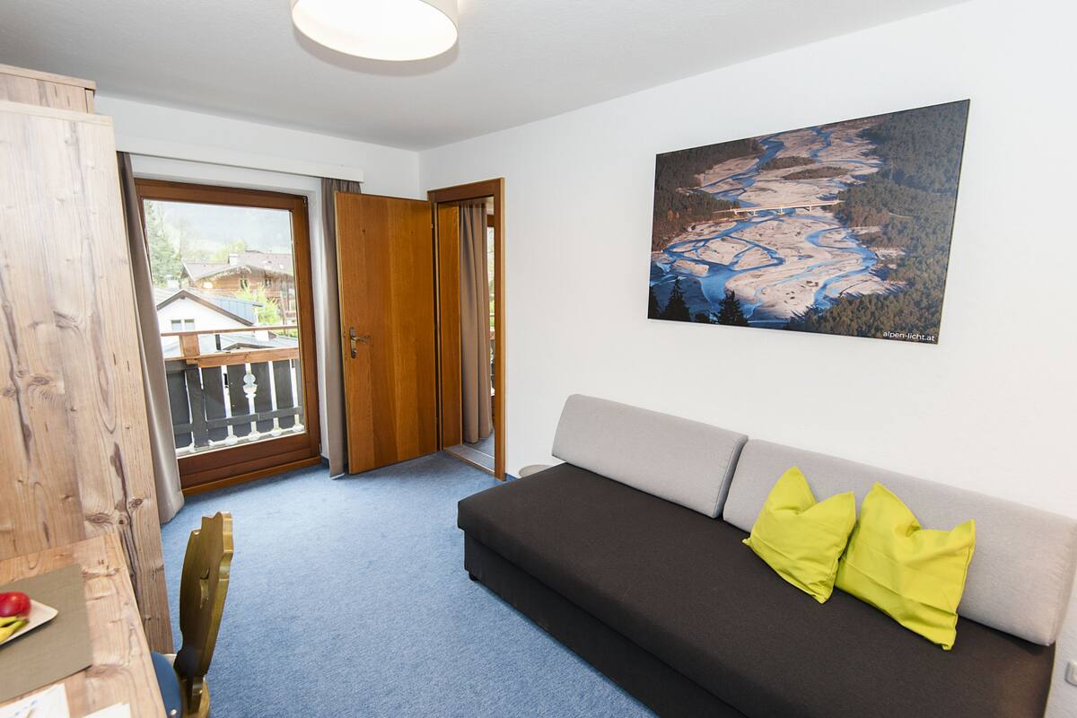 A room with a sofa, a painting, and a view through a door.