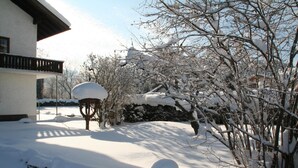 A snow-covered landscape with a building featuring a balcony. - Pension Leuprecht (Lechaschau)