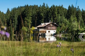 Una casa junto a un lago, con muelle de madera y una pequeña plataforma.