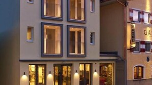 A modern hotel with a flat facade, multiple balconies, and large windows. - Pension Leuprecht (Lechaschau)
