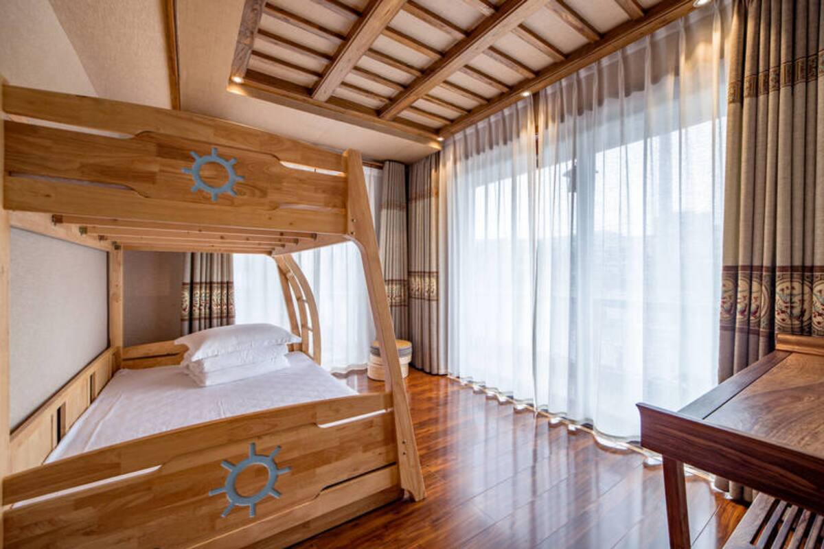 A wooden bunk bed with a sun design, a wooden table, and curtains.