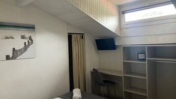 Une chambre d’hôtel comprenant un lit, un bureau, une chaise, une télévision et une armoire.