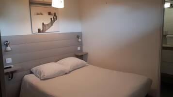 Un lit bien fait, avec une tête de lit, des lampes de chevet et une œuvre d’art accrochée au mur.