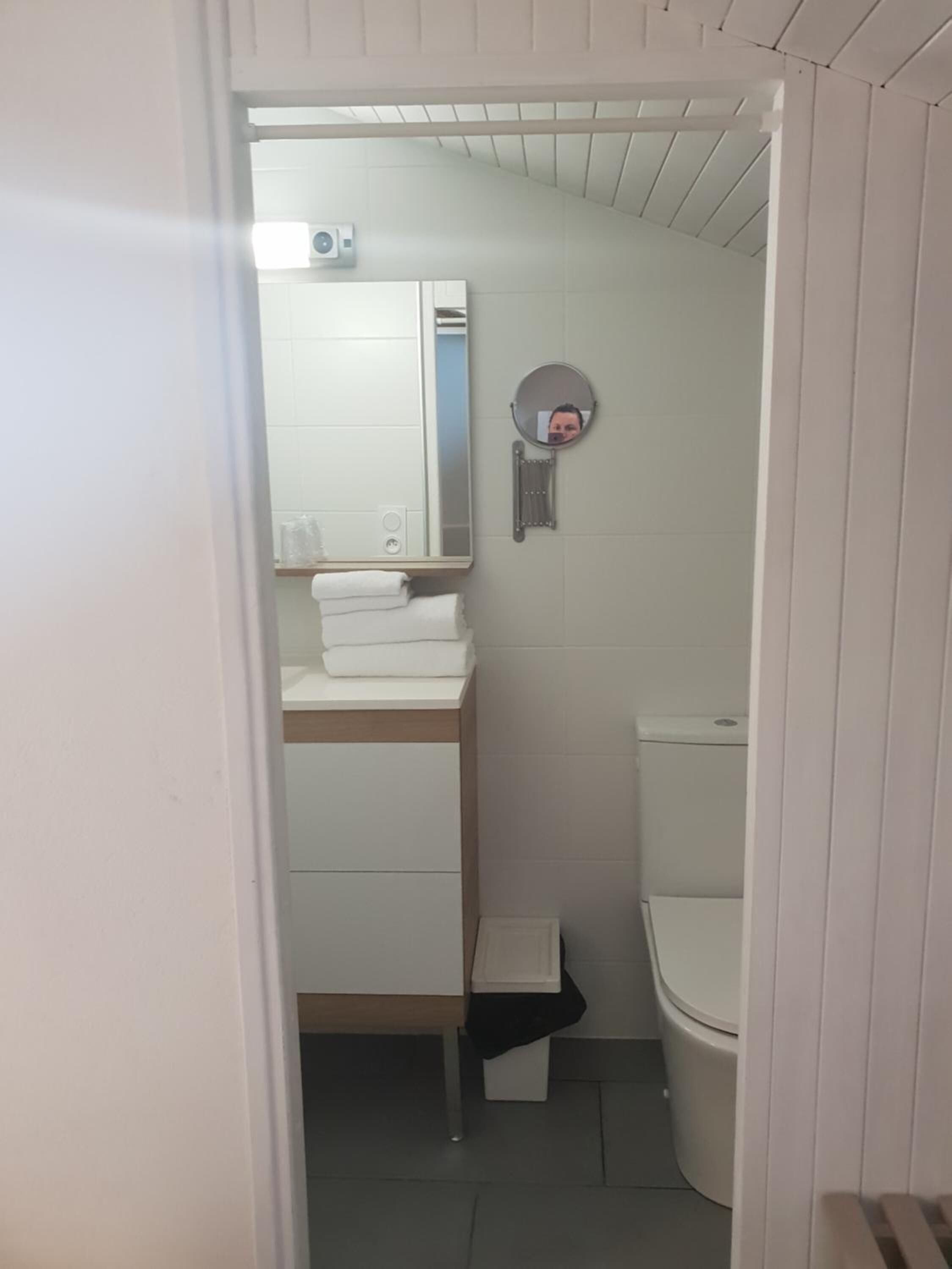 A small, compact bathroom with a toilet, a sink with a mirror, and a towel rack.