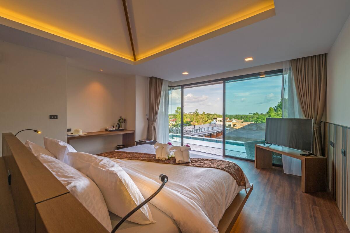 Et moderne hotelværelse med en stor seng, fjernsyn, skrivebord og udsigt over byen.