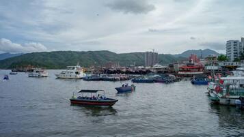 A harbor with multiple boats docked, a mountainous backdrop, and a building with a crane.