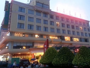 A multi-story hotel with a prominent entrance, a flag, and a parking area. - Wanghailou Hotel (Huizhou)