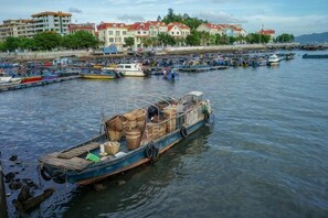 A harbor with boats docked, a waterfront building, and a clear sky. - Wanghailou Hotel (Huizhou)