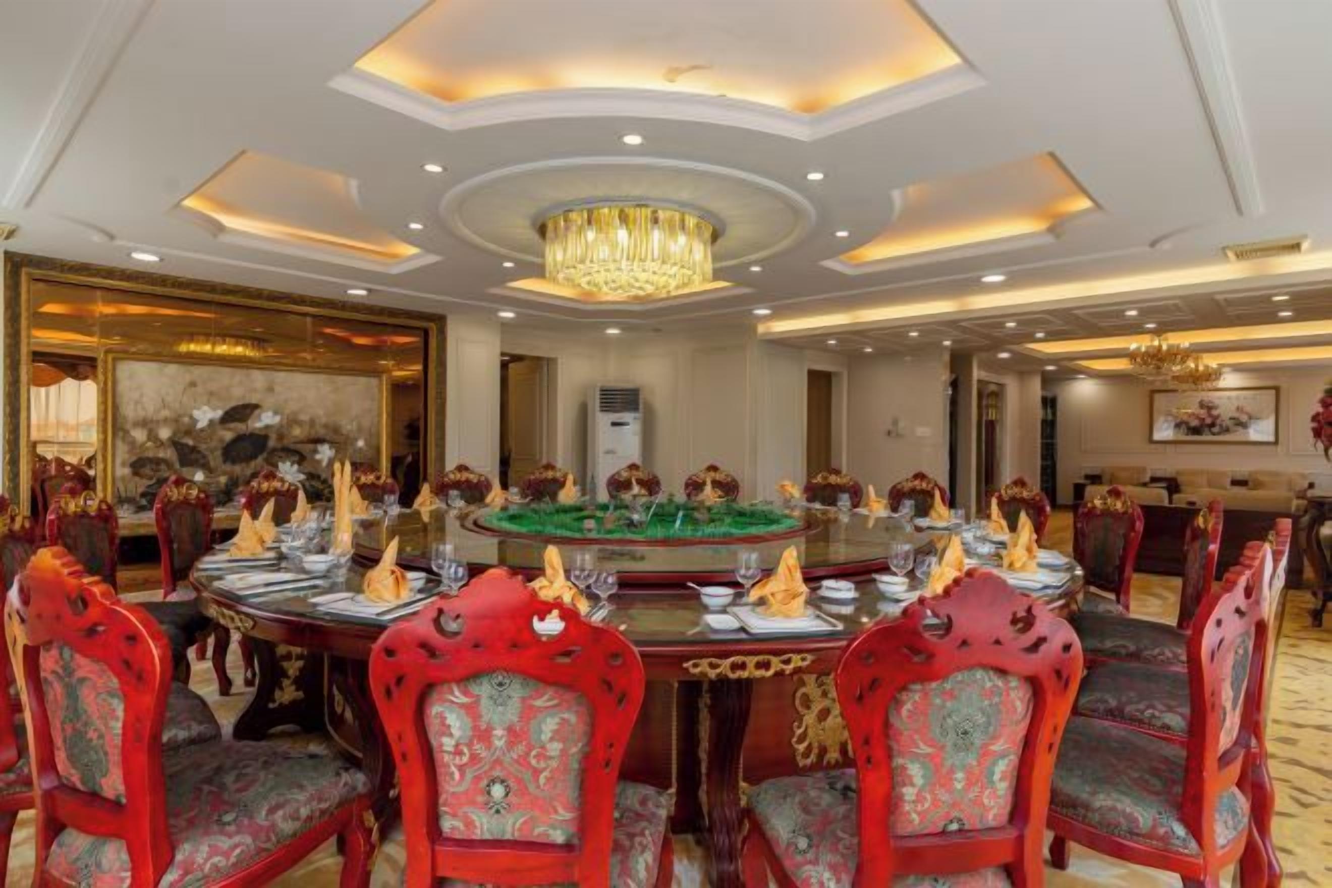 Une salle à manger élégante, avec une table ronde, des chaises richement décorées et un lustre.