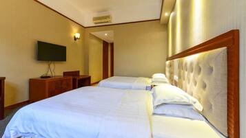 A hotel room with two beds, a flat-screen TV, a wooden dresser, and a wall-mounted air conditioning unit.