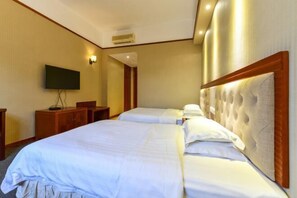 A hotel room with two beds, a flat-screen TV, a wooden dresser, and a wall-mounted air conditioning unit. - Wanghailou Hotel (Huizhou)