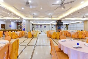 A banquet hall with rows of tables and chairs, ceiling fans, and a stage area. - Wanghailou Hotel (Huizhou)