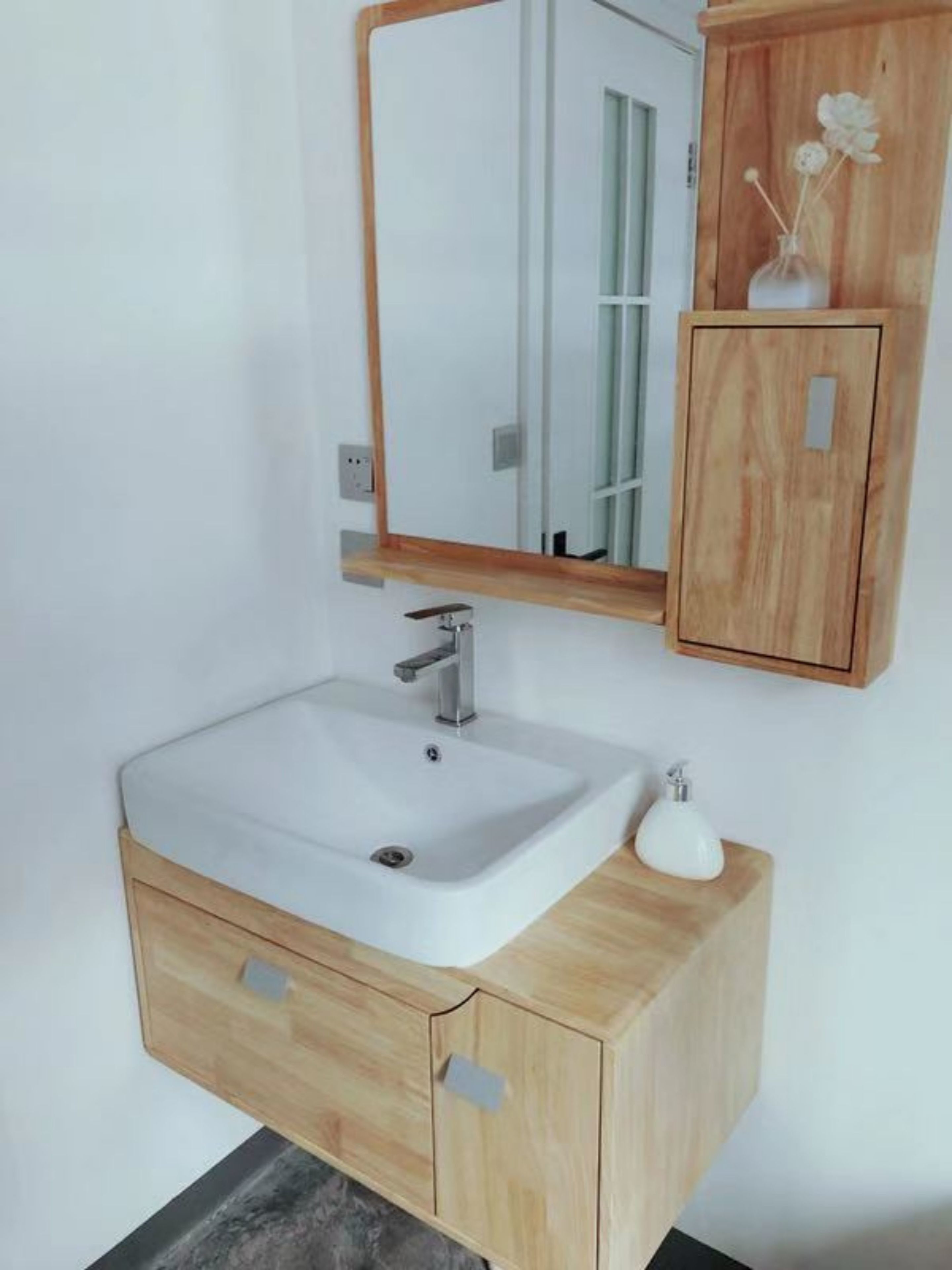 A bathroom with a white sink, wooden cabinet, and a mirror.