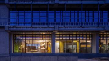 Un edificio moderno con amplios ventanales y espacio de oficina visible en su interior.