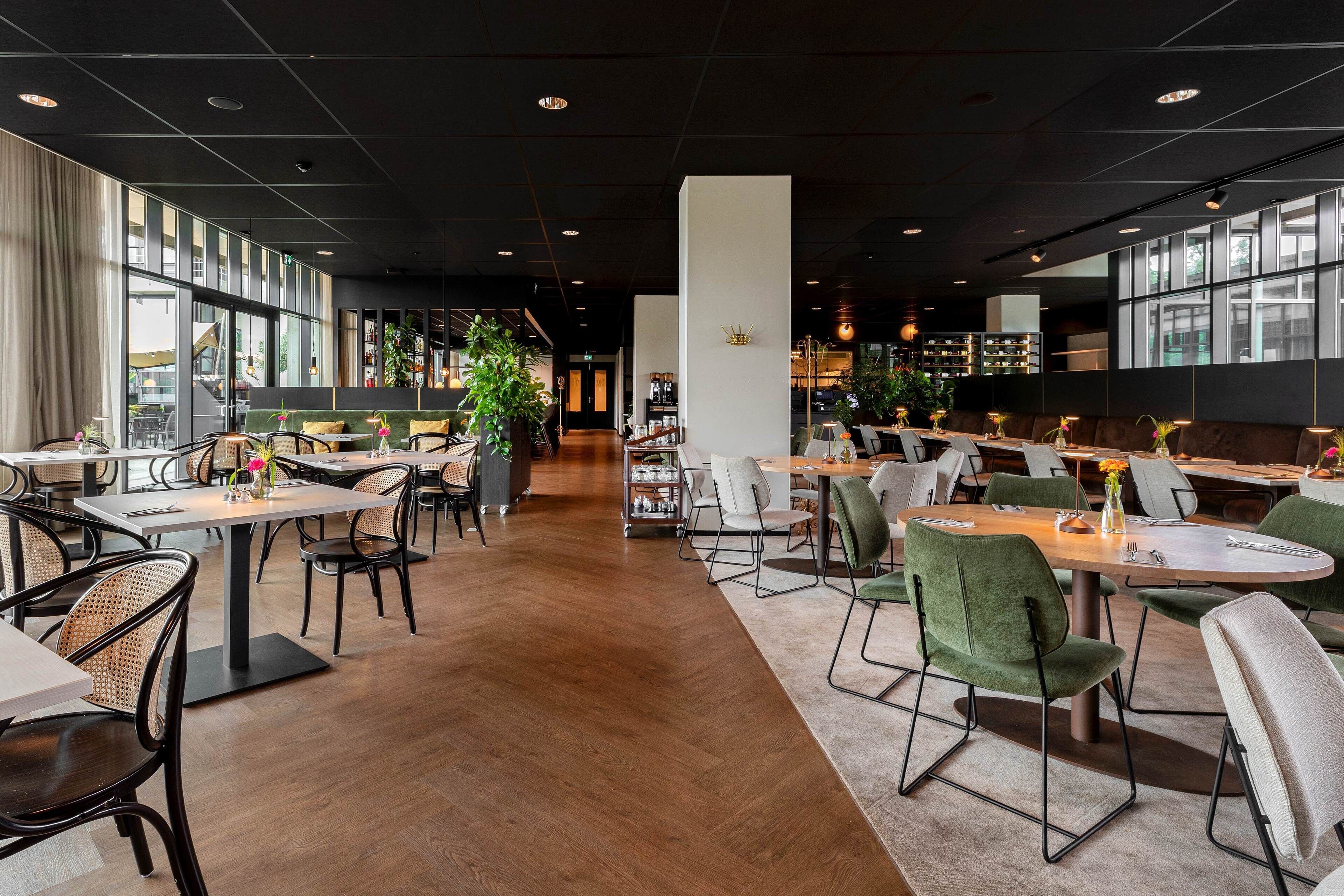 A modern restaurant with high ceilings, large windows, and a variety of seating options including tables and booths.