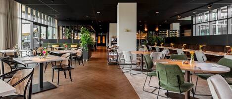 A modern restaurant with high ceilings, large windows, and a variety of seating options including tables and booths.