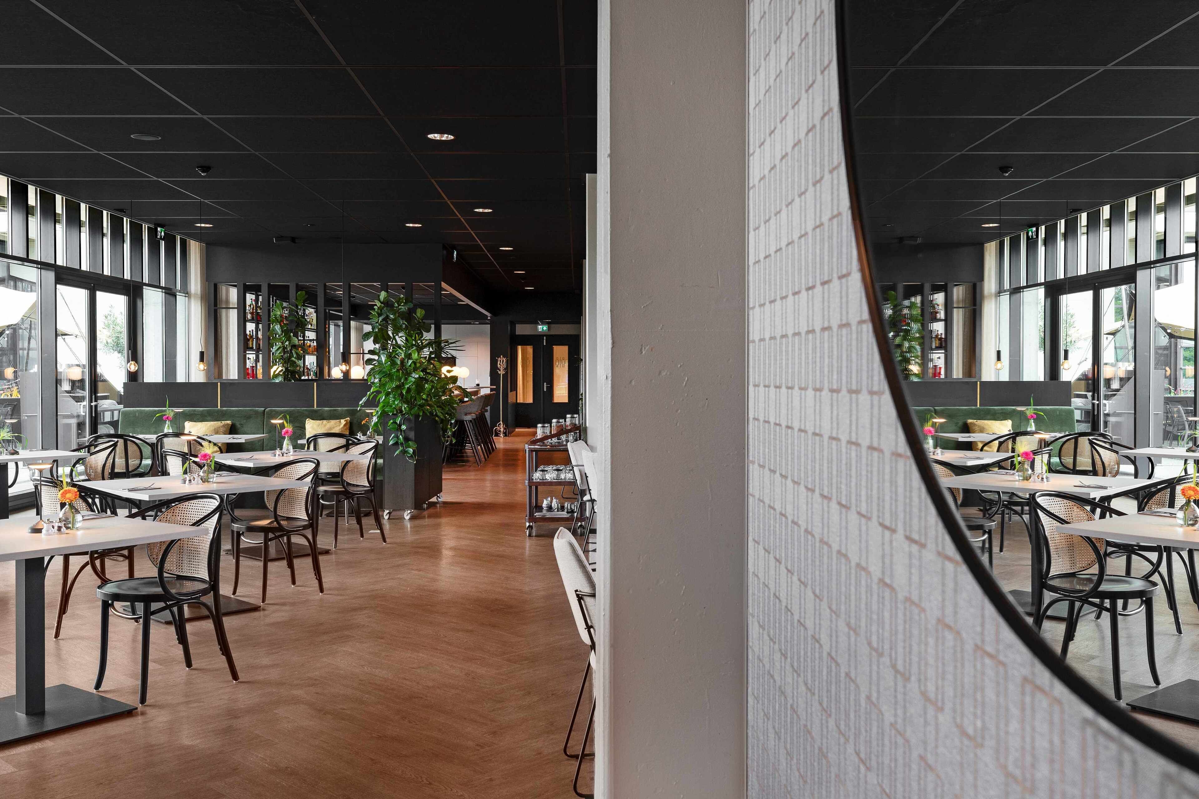 Ein modernes Restaurant mit einer langen Theke, Holzboden und großen Fenstern.