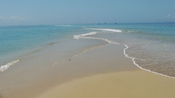 Ein Strand mit klarem Wasser und sandigem Ufer.