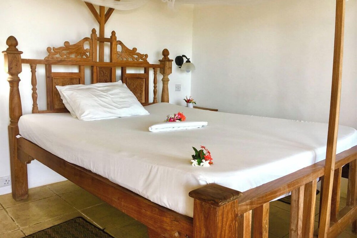 Un letto di legno con materasso bianco e testiera in legno.