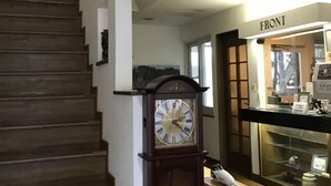Una escalera de madera conduce a una plataforma. Un reloj abuelo se encuentra en la plataforma.