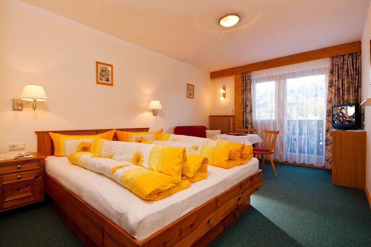Una habitación de hotel con una cama grande, dos mesitas de noche, un escritorio, una silla y un televisor.