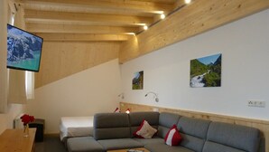 Ett mysigt rum med en grå soffa, ett träbord och en tv som är monterad på väggen.
