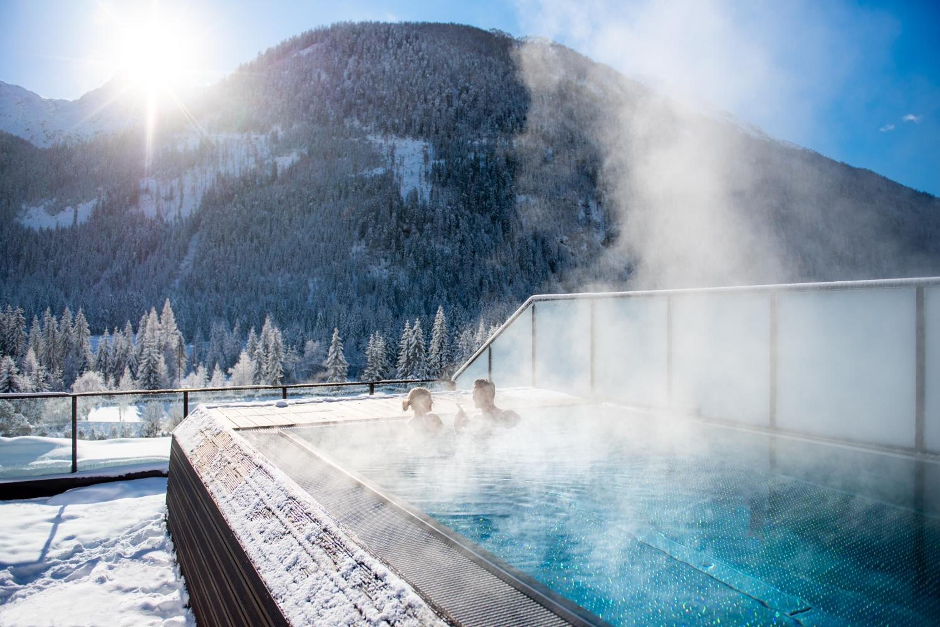 A hot spring with a view of snow-covered mountains and trees.