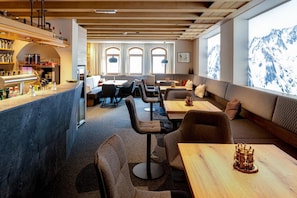 A modern interior with a bar area, seating arrangements, and large windows.