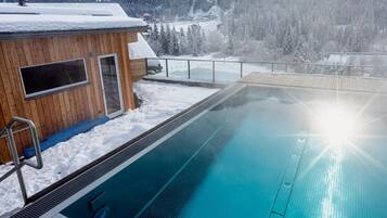 Una piscina con un edificio in legno adiacente, sullo sfondo montagne.