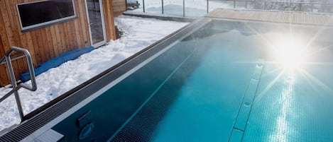 A swimming pool with a wooden building adjacent to it, set against a mountainous backdrop.
