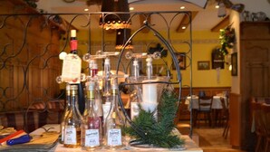 Uma área de bar com uma estante de metal exibindo diversas garrafas, uma vela e um pequeno ramo de pinheiro.
