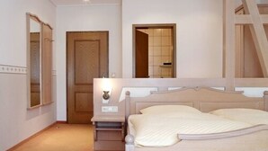 Quarto com cama, mesa de cabeceira, espelho e porta.