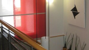 A staircase with a metal railing, a red panel, and a wall-mounted geometric decoration. - Maurers Zollamt Hotel (Kaiserslautern)