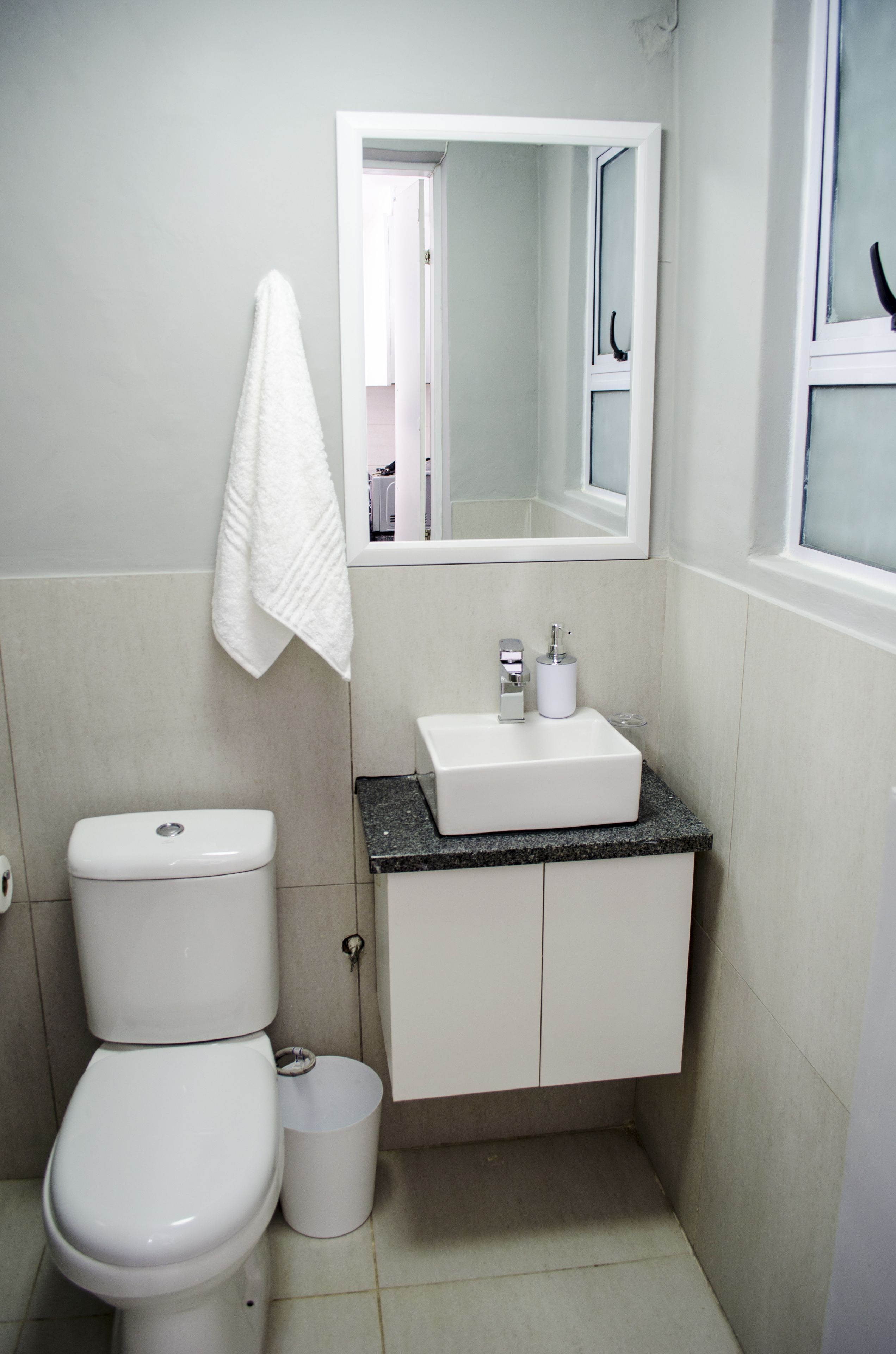 A small bathroom with a white toilet, a sink, and a mirror above the sink.