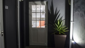 A hallway with a white door marked 106, a potted plant, and a number 107 sign on the wall. - Cape Town Micro Apartments (Cape Town)
