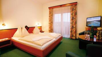 A hotel room with a bed, a desk, a chair, a television, and a window with curtains.