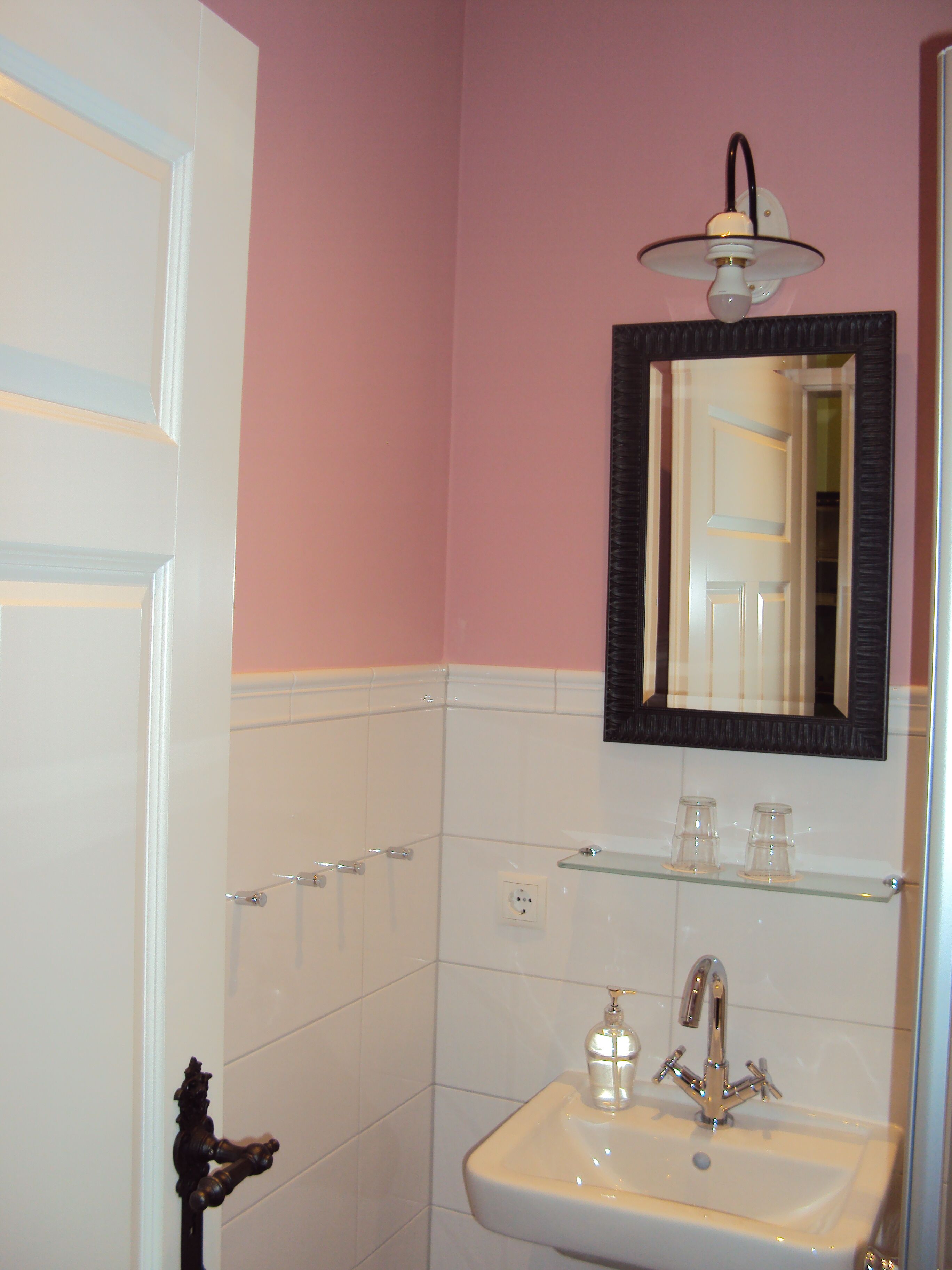A bathroom with a white sink, a mirror, and a light fixture above it.