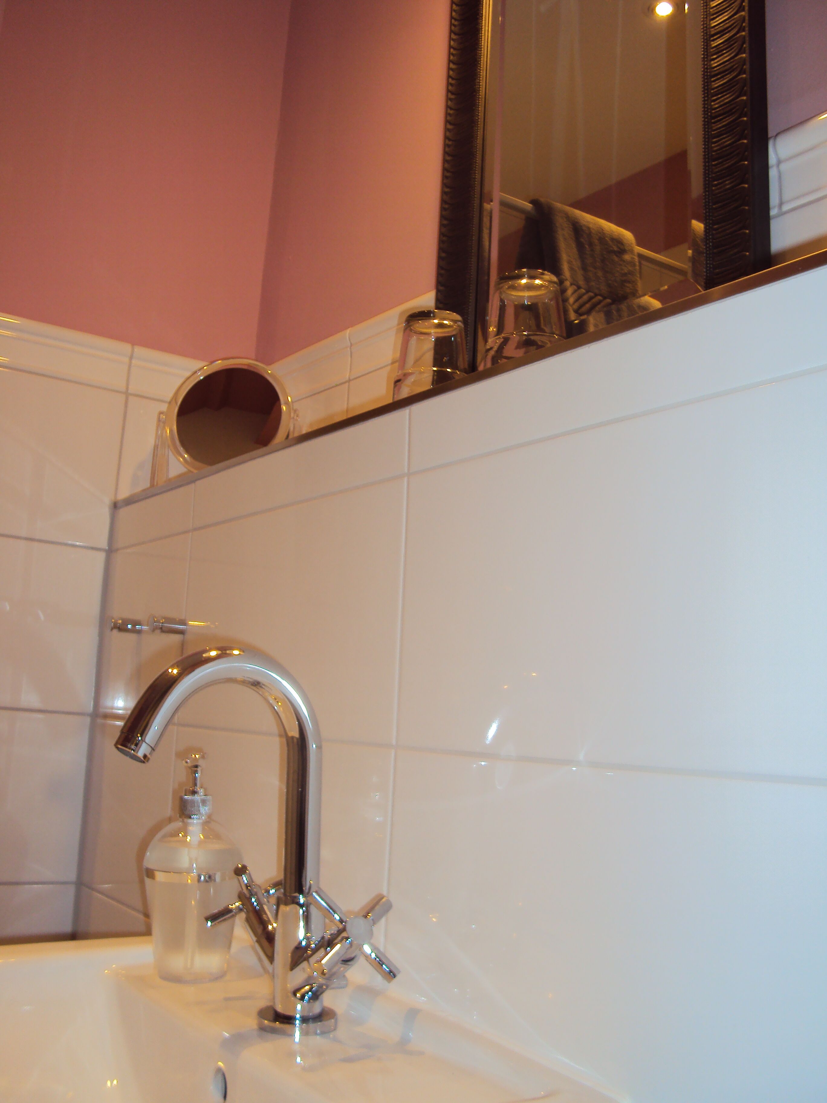A bathroom with a white sink, chrome faucet, and a mirror above it.