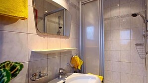 A bathroom with a white sink, mirror, and shower enclosure. - Baumgartnerhof (Finkenstein am Faaker See)