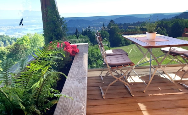 A deck with a table and chairs overlooking a mountainous landscape.