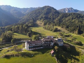 A large building with multiple rooms, surrounded by green fields and forested hills. - Baumgartnerhof (Finkenstein am Faaker See)